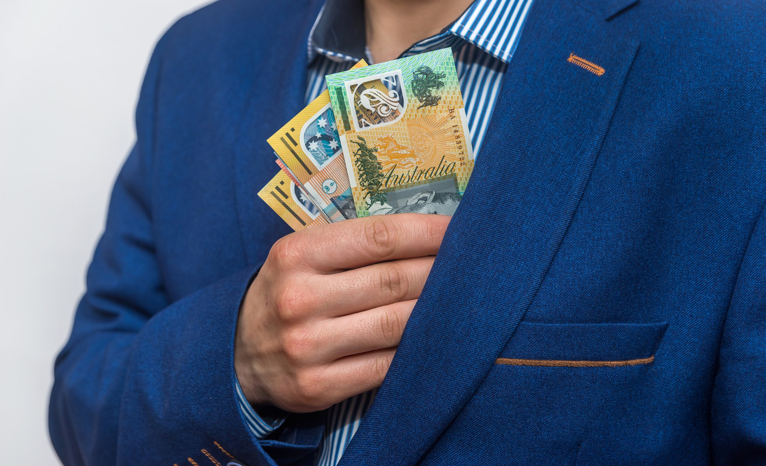 male hand hiding australian dollar banknotes into pocket