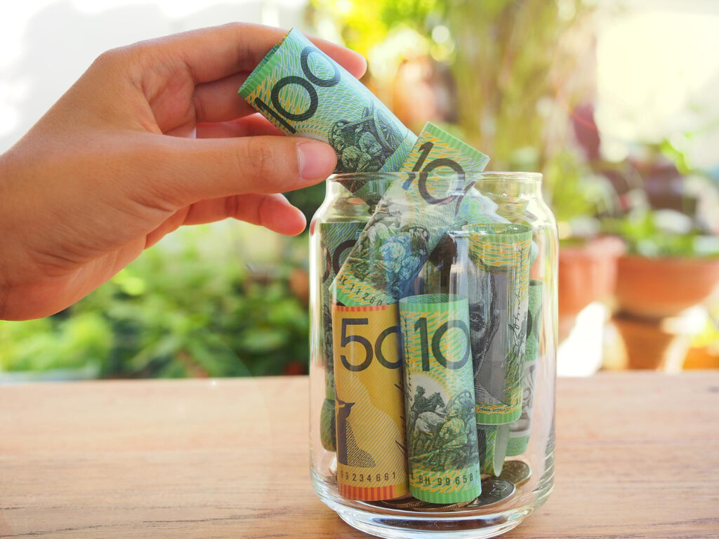 woman hand put australia bank note glass saving money concept